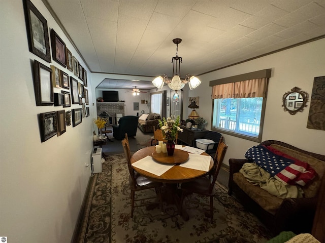 dining room with a brick fireplace and ceiling fan with notable chandelier