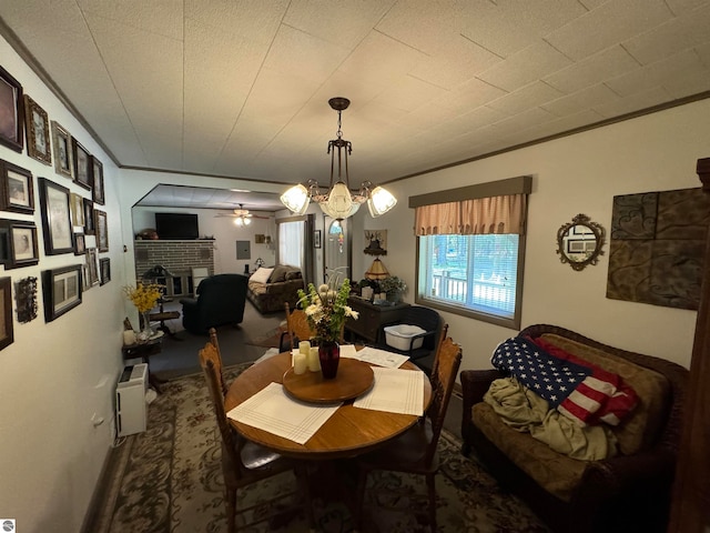 dining room with ceiling fan with notable chandelier and a fireplace