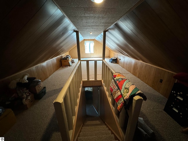 interior space featuring wooden walls, lofted ceiling, and carpet floors