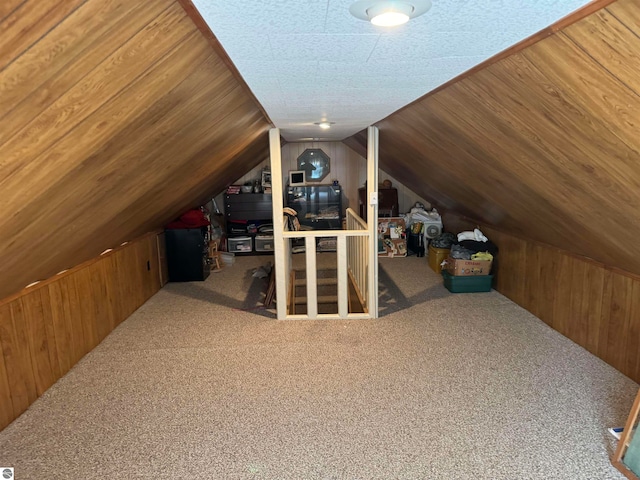 bonus room with carpet, wood walls, and vaulted ceiling