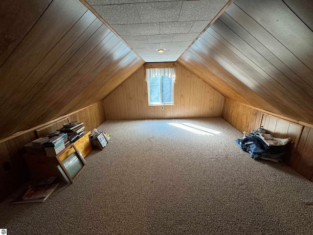 bonus room with carpet floors, wooden walls, and vaulted ceiling