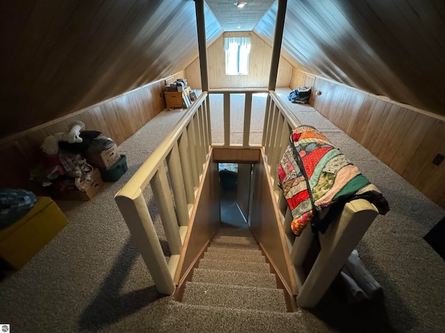 stairway featuring carpet floors, wood walls, and vaulted ceiling