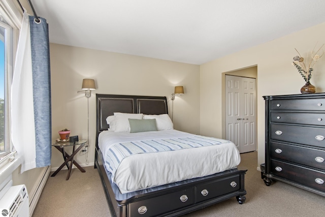 bedroom featuring a baseboard heating unit, light carpet, and a closet