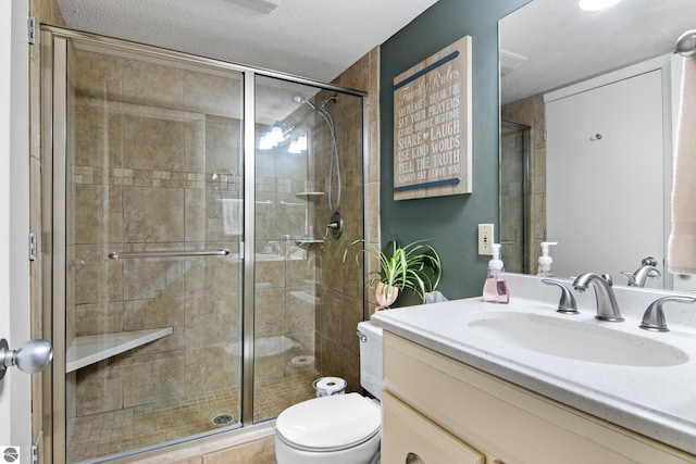 bathroom featuring a textured ceiling, an enclosed shower, vanity, and toilet