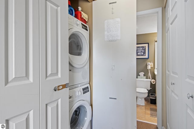 laundry area featuring stacked washer / dryer and tile patterned floors