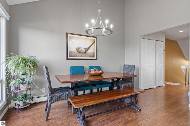 dining room with a chandelier, baseboard heating, and hardwood / wood-style floors