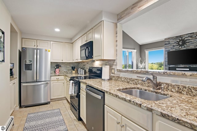 kitchen with light stone counters, a baseboard radiator, appliances with stainless steel finishes, and sink