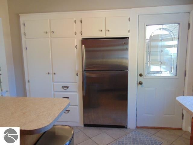 kitchen featuring white cabinetry, light tile patterned floors, and stainless steel refrigerator