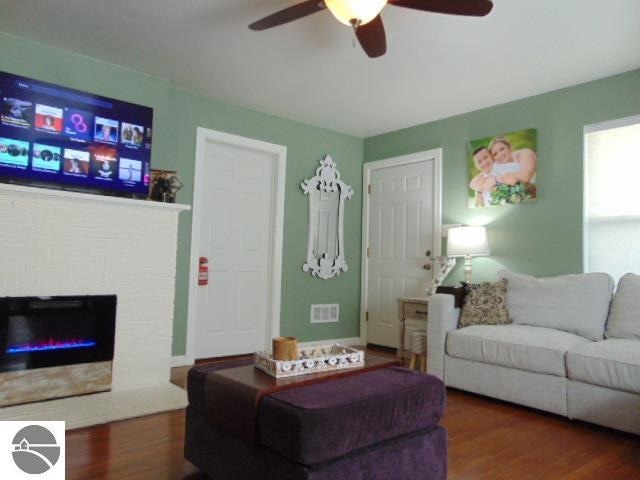 living room with ceiling fan, a fireplace, and dark hardwood / wood-style flooring