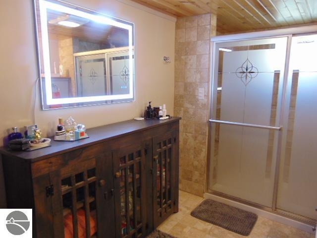 bathroom with a shower with shower door and wooden ceiling