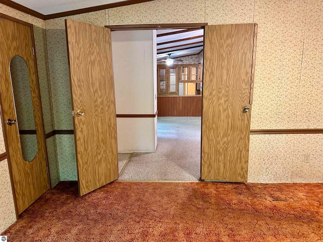 corridor with dark carpet, ornamental molding, and vaulted ceiling