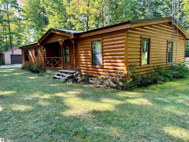 log cabin with a front yard and an outbuilding