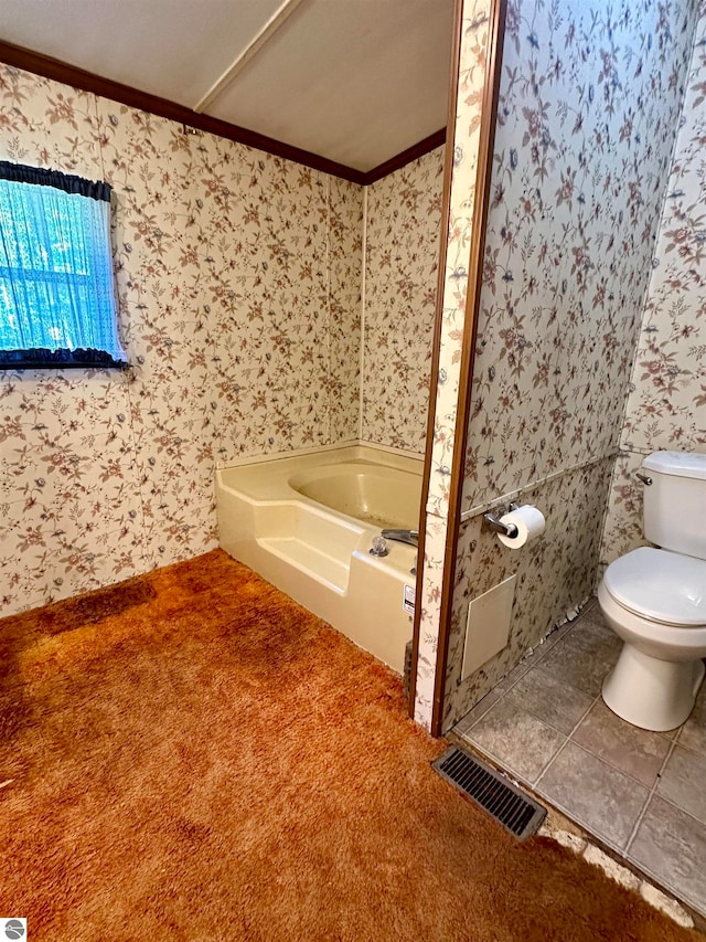 bathroom with a bathing tub, crown molding, and toilet