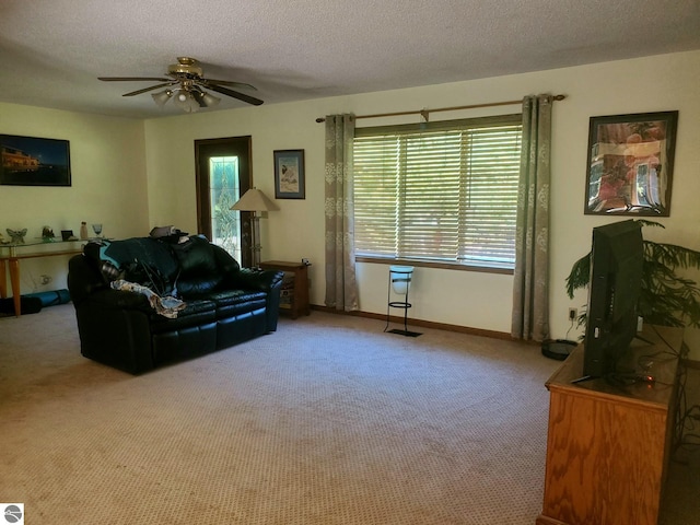 carpeted living room featuring ceiling fan and a textured ceiling