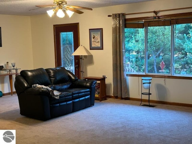 carpeted living room featuring ceiling fan and a textured ceiling