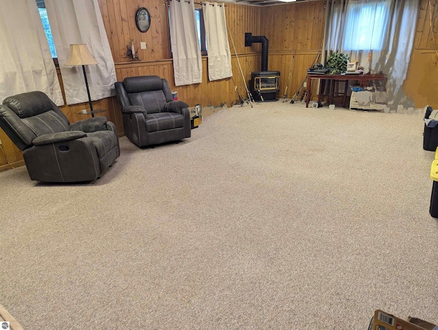 sitting room featuring wooden walls, carpet, and a wood stove