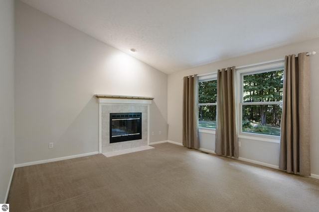 unfurnished living room with a fireplace, vaulted ceiling, and light colored carpet