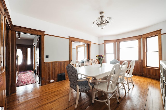 dining room featuring a notable chandelier, wood-type flooring, and wooden walls