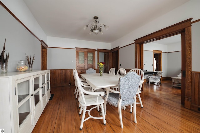 dining room featuring wooden walls, a chandelier, and hardwood / wood-style flooring