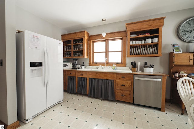 kitchen with white appliances, hanging light fixtures, and sink