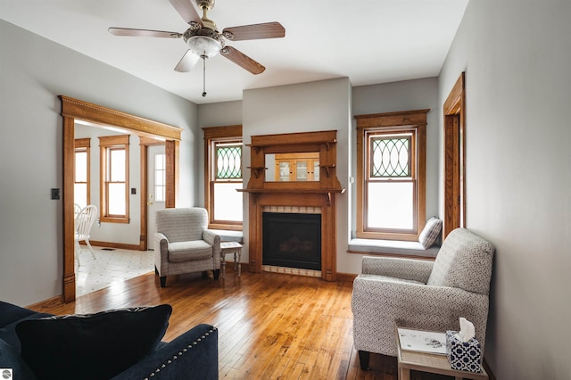 living room featuring a fireplace, ceiling fan, and light hardwood / wood-style flooring