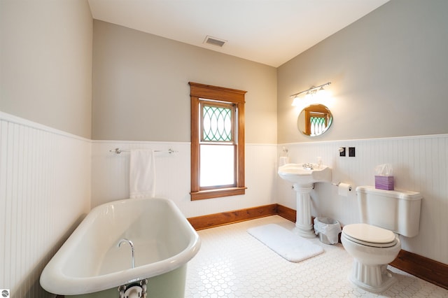 bathroom featuring a washtub, tile patterned flooring, and toilet