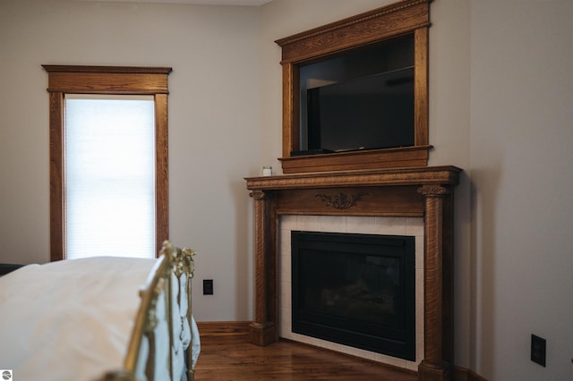 bedroom with a tile fireplace and dark hardwood / wood-style flooring