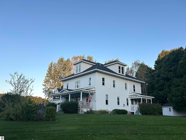 view of front of home featuring a storage unit, a front lawn, and covered porch