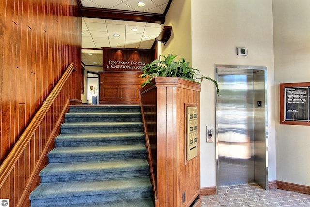 staircase featuring wood walls and elevator