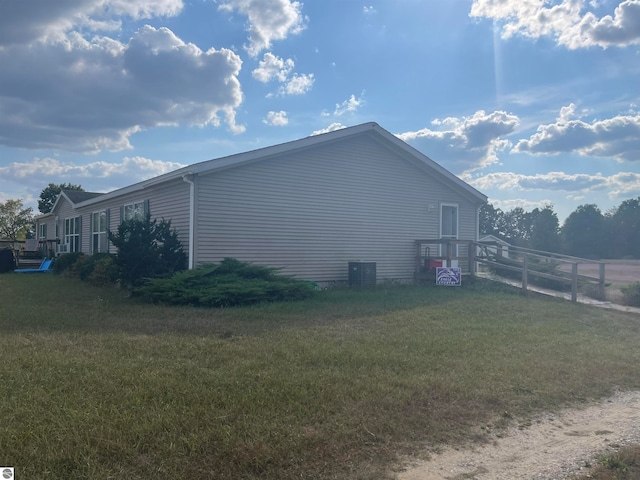 view of side of home with central AC unit and a yard