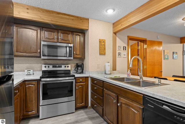 kitchen featuring sink, kitchen peninsula, a textured ceiling, light hardwood / wood-style flooring, and stainless steel appliances