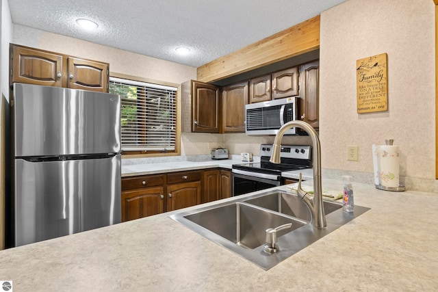 kitchen with a textured ceiling, stainless steel appliances, and carpet