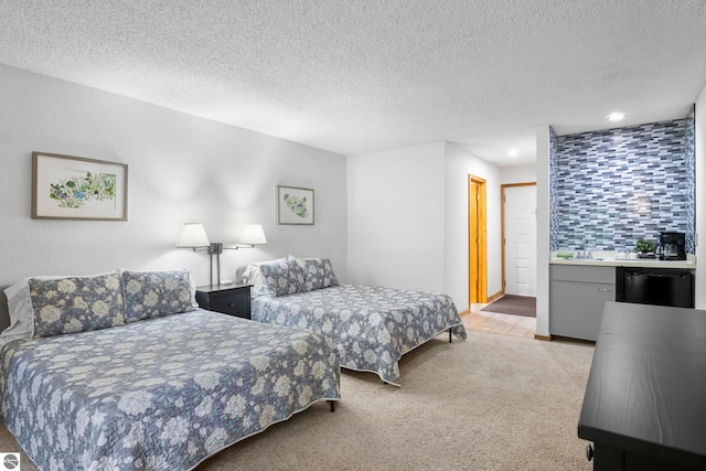 bedroom with a textured ceiling, sink, light colored carpet, and a closet