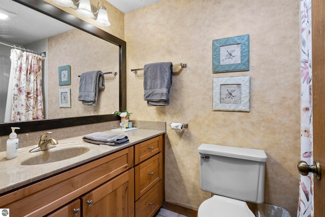 bathroom with a textured ceiling, vanity, and toilet