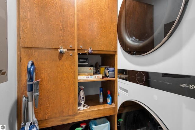 washroom with stacked washing maching and dryer and cabinets