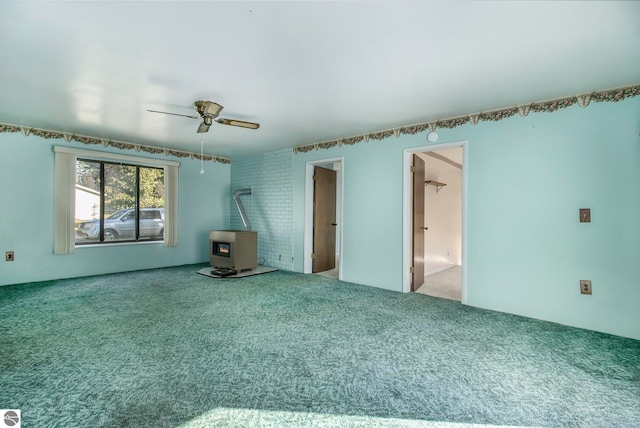 carpeted spare room with ceiling fan and a wood stove