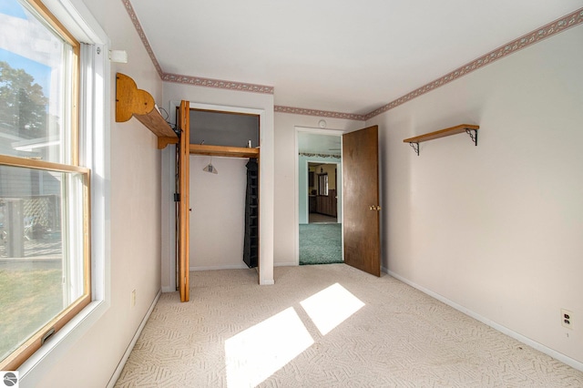 unfurnished bedroom featuring a closet, multiple windows, and light colored carpet