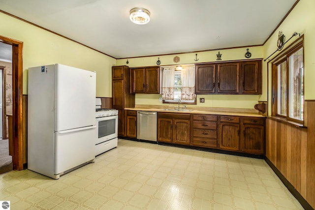 kitchen featuring crown molding, white appliances, wooden walls, and sink