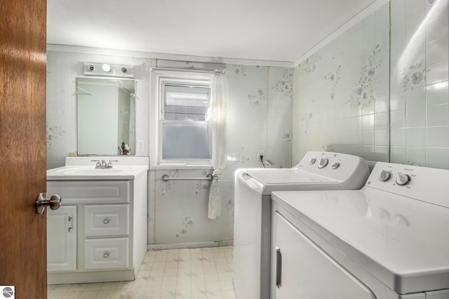 clothes washing area featuring ornamental molding, tile walls, and independent washer and dryer