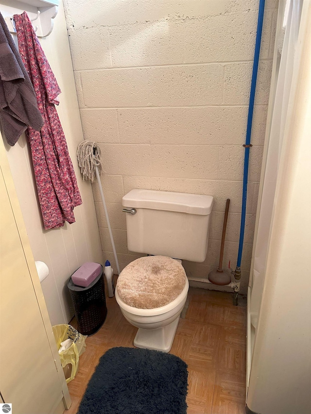 bathroom featuring parquet flooring and toilet