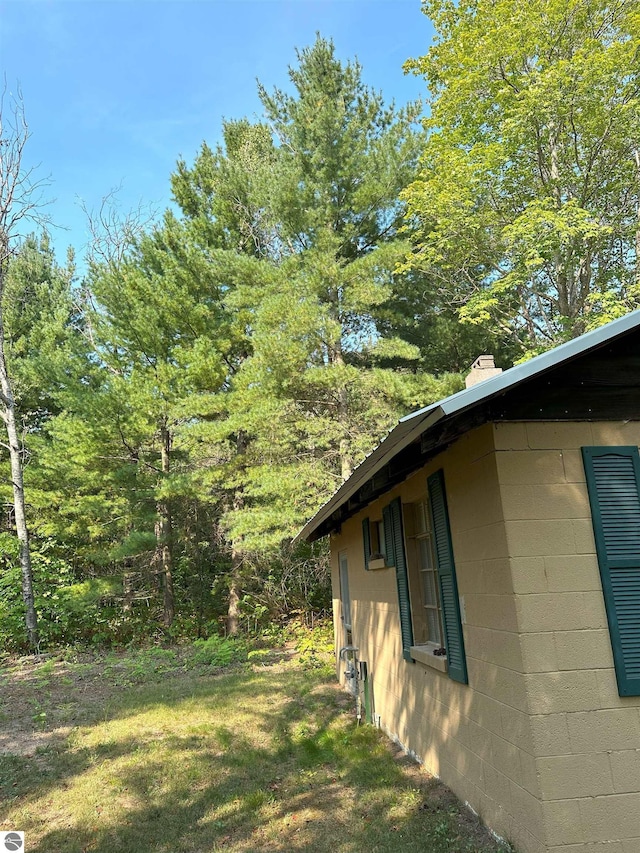 view of home's exterior featuring a lawn, concrete block siding, and a chimney