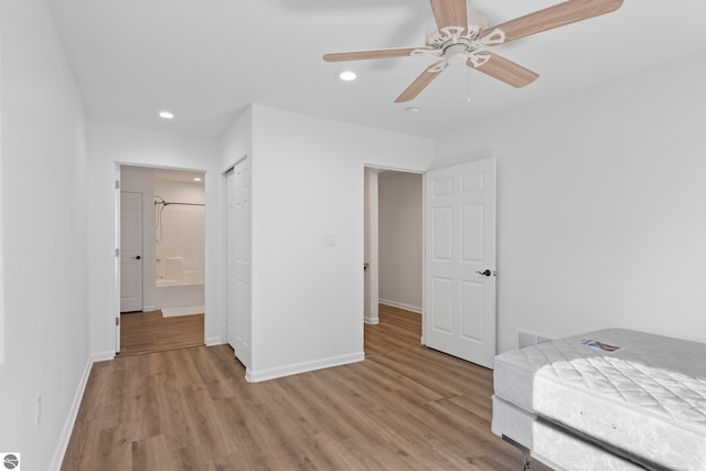 unfurnished bedroom with ceiling fan, light wood-type flooring, and ensuite bath