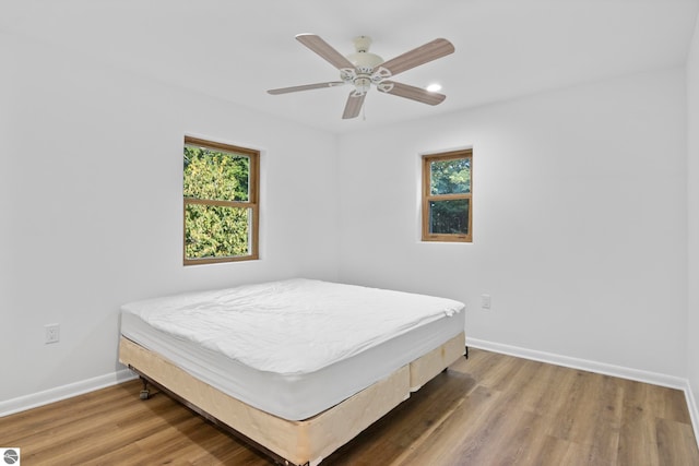 bedroom with ceiling fan, multiple windows, and hardwood / wood-style floors