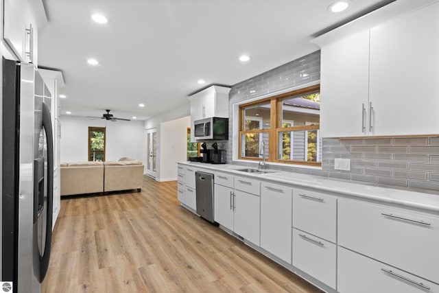 kitchen featuring ceiling fan, tasteful backsplash, white cabinetry, stainless steel appliances, and light wood-type flooring