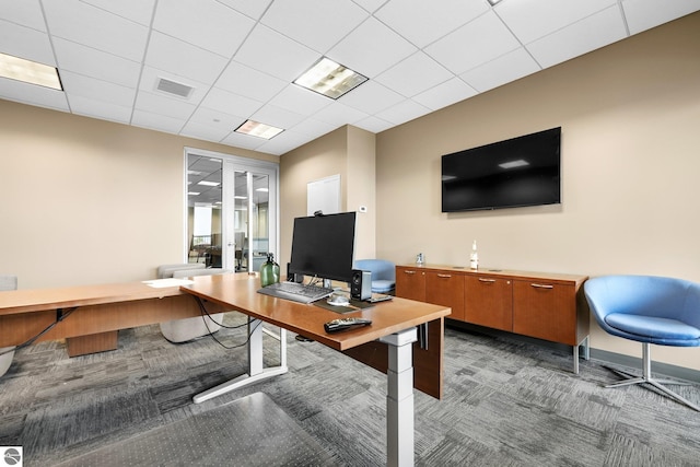 carpeted office space featuring a paneled ceiling