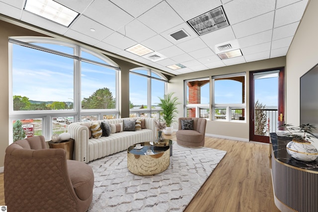 living room featuring light hardwood / wood-style flooring, a drop ceiling, and a wealth of natural light