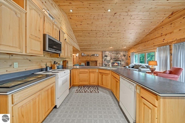 kitchen with wood walls, white appliances, light brown cabinets, and kitchen peninsula