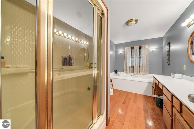 bathroom with hardwood / wood-style flooring, vanity, and shower with separate bathtub