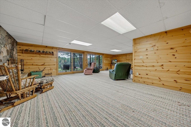 unfurnished room featuring carpet floors, wooden walls, and a paneled ceiling