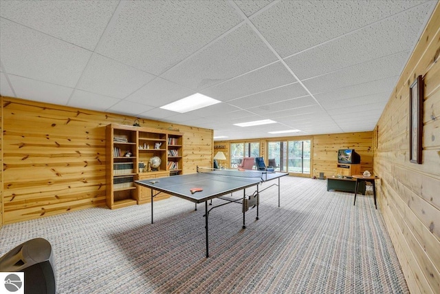 recreation room featuring a drop ceiling and wooden walls